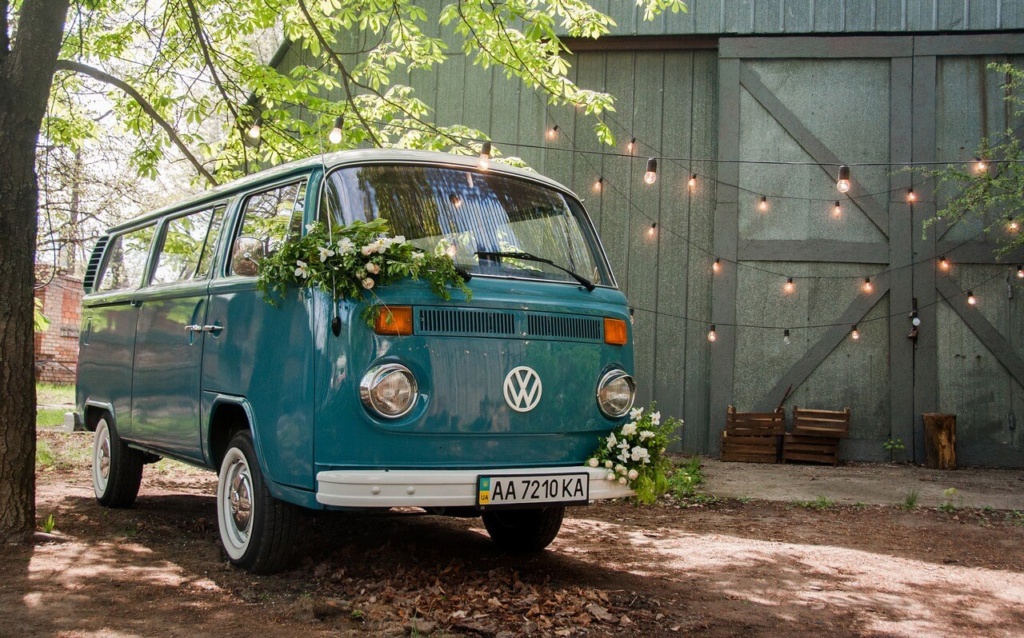 Blauer VW Bulli Oldtimer als Hochzeitsfahrzeug mit Blumenschmuck